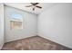 This bedroom has neutral carpet, a ceiling fan with lights, and a window to let in natural light at 21075 E Estrella Rd, Queen Creek, AZ 85142