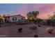 The spacious backyard with a fence, trees, and open space beneath a pink sunset sky at 22216 W Bajada Dr, Wittmann, AZ 85361