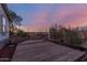 Backyard with a deck, fence, and trees under a colorful sky at dusk at 22216 W Bajada Dr, Wittmann, AZ 85361