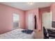 A view of a small pink bedroom with a bed, window, closet, and doorway to another room at 22216 W Bajada Dr, Wittmann, AZ 85361