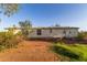 View of the side of a single-story home with a small tree in a red dirt lot at 22216 W Bajada Dr, Wittmann, AZ 85361