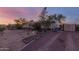 Exterior of ranch home featuring mature landscape, a covered porch, and gravel driveway at 22216 W Bajada Dr, Wittmann, AZ 85361