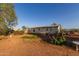 Single-story home with red dirt lot and trees under a beautiful clear blue sky at 22216 W Bajada Dr, Wittmann, AZ 85361