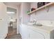 A small laundry room with white washer and dryer, shelves, and a doorway to another room at 22216 W Bajada Dr, Wittmann, AZ 85361