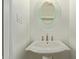All-white powder room with a pedestal sink and decorative mirror at 3350 W Las Palmaritas Dr, Phoenix, AZ 85051
