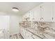 A well-lit kitchen featuring white cabinetry, marble countertops, and laminate flooring at 3350 W Las Palmaritas Dr, Phoenix, AZ 85051