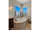 Elegant bathroom with a luxurious soaking tub under two windows, and dark wood vanity at 36813 N 109Th Way, Scottsdale, AZ 85262