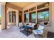 Covered patio with stone flooring, lounge furniture, and large windows showcasing the outdoor view at 4041 N Silver Ridge Cir, Mesa, AZ 85207