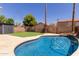 Backyard pool featuring artificial grass, a storage shed, and desert landscaping on a sunny day at 4514 E Verbena Dr, Phoenix, AZ 85044