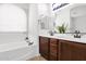 Bright bathroom featuring a soaking tub, dual vanity with brown cabinets and tile floors at 7261 E Norland St, Mesa, AZ 85207