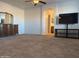 Spacious bedroom featuring plush carpeting, ceiling fan and TV console with a glimpse into the ensuite bathroom at 7321 S 48Th Dr, Laveen, AZ 85339