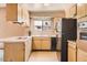 Bright kitchen featuring wood cabinets, a window over the sink, and a black refrigerator and oven at 736 E Loyola Dr, Tempe, AZ 85282