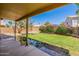 Backyard showcasing a covered patio, lush lawn, colorful bougainvillea, and mature trees under a clear blue sky at 8478 W Grovers Ave, Peoria, AZ 85382
