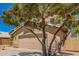 Close up of home featuring desert landscaping, a two-car garage, and a mature shade tree at 8478 W Grovers Ave, Peoria, AZ 85382