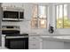 Close up on modern stainless steel oven, cooktop, and sink with quartz countertops at 8478 W Grovers Ave, Peoria, AZ 85382