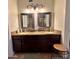 Bathroom featuring a dual sink vanity with dark wood cabinets and a decorative lighting fixture at 8908 W Sheridan St, Phoenix, AZ 85037