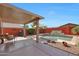 Spacious covered patio with outdoor seating, overlooking a pool with a water feature in landscaped backyard at 10786 W Chisholm Dr, Sun City, AZ 85373
