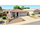 Inviting single-story home featuring desert landscaping, tile roof, paved driveway, and solar panels for energy efficiency at 10786 W Chisholm Dr, Sun City, AZ 85373