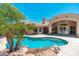Beautiful backyard featuring a pool with a rock waterfall and lush palm trees at 12120 E Cortez Dr, Scottsdale, AZ 85259