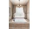 Soaking tub with granite surround and a window with glass blocks for natural light at 12120 E Cortez Dr, Scottsdale, AZ 85259