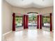 Bright living room featuring large windows with backyard views, tile floors, and red curtains at 12120 E Cortez Dr, Scottsdale, AZ 85259