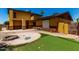 Backyard with an artificial lawn and a custom-built stone fire pit area, perfect for entertaining guests at 12459 N 36Th St, Phoenix, AZ 85032