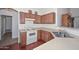 Well-lit kitchen featuring wood cabinets, white appliances, and views into adjacent rooms at 1527 S 219Th Ln, Buckeye, AZ 85326