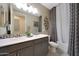 Well-lit bathroom featuring a double vanity and a shower with patterned tile at 18835 W San Miguel Ave, Litchfield Park, AZ 85340