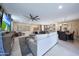 Spacious living room with an oversized sectional sofa, modern ceiling fan, and an open floor plan to the kitchen at 18835 W San Miguel Ave, Litchfield Park, AZ 85340