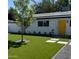 Charming single-story home boasts a modern front yard with synthetic grass and a vibrant yellow front door at 2201 N 29Th Pl, Phoenix, AZ 85008