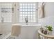 Close up of a free-standing tub with black hardware, walk in shower, tile accent wall and a glass block window at 2881 E Estrella Ct, Gilbert, AZ 85296