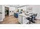 Well-lit kitchen featuring white cabinets, a blue island, marble countertops, and barstool seating at 2881 E Estrella Ct, Gilbert, AZ 85296