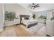 Light-filled primary bedroom boasts hardwood floors, a ceiling fan, and large windows with views of the greenery at 2881 E Estrella Ct, Gilbert, AZ 85296