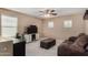 Neutral living room featuring a dark brown couch, ceiling fan, television, ottoman, and window at 3080 E Andre Ave, Gilbert, AZ 85298