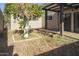 Serene backyard featuring a covered patio, desert landscaping, and a mature tree at 3345 E University Dr # 2, Mesa, AZ 85213