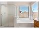 Bright bathroom featuring a soaking tub with a large window, and a glass shower at 3550 E Topeka Dr, Phoenix, AZ 85050