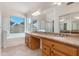 Bathroom with double vanity, granite counters, soaking tub, and large window at 3550 E Topeka Dr, Phoenix, AZ 85050