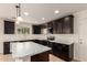 Modern kitchen features an island with white marble countertops and dark cabinetry at 38191 W Merced St, Maricopa, AZ 85138