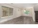 Bright living room with modern gray wood floors, large windows, and staircase at 38191 W Merced St, Maricopa, AZ 85138