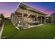 Outdoor living space featuring a covered patio with comfortable seating, lush green lawn, and sunset views at 42105 N Golf Crest Rd, Anthem, AZ 85086