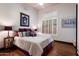 Bright bedroom with shuttered windows, hardwood floors, a comfortable bed with decorative pillows, and elegant decor at 42105 N Golf Crest Rd, Anthem, AZ 85086