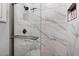 Luxurious shower with marble-patterned tile, a glass door, and a built-in shelf for toiletries in bathroom at 42105 N Golf Crest Rd, Anthem, AZ 85086