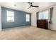 A spacious bedroom featuring two windows, neutral carpet, and a dark wood dresser at 42616 W Avella Dr, Maricopa, AZ 85138