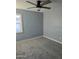 This comfortable bedroom includes gray walls, soft carpet, a ceiling fan, and a bright window at 6216 S 5Th Ave, Phoenix, AZ 85041