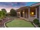 This backyard has a covered patio with a kitchen area, a putting green, and a stone waterfall at 645 W Longhorn Dr, Chandler, AZ 85286