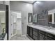Bathroom showcasing dual sinks, dark gray vanity, large mirror, gray walls, and an open door to the closet at 645 W Longhorn Dr, Chandler, AZ 85286