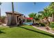 Backyard area with artificial turf, a covered patio, a pool, and palm trees at 717 N Mckemy Ave, Chandler, AZ 85226