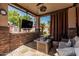 Covered patio with an outdoor television, travertine floors, and a stone wall at 717 N Mckemy Ave, Chandler, AZ 85226