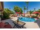 Inviting backyard pool area with palm trees, lounge chairs, umbrellas, and a rock waterfall feature at 717 N Mckemy Ave, Chandler, AZ 85226