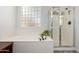 Bright bathroom featuring a soaking tub, a glass-enclosed shower, and a textured glass window at 723 E Gemini Pl, Chandler, AZ 85249